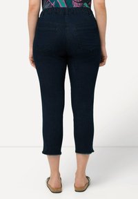 Jeans in denim blu scuro, taglio cropped, con una vestibilità rilassata, dotati di una vita elastica, due tasche posteriori e dettagli sull'orlo sfrangiati.