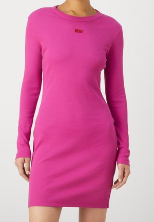 Aansluitend lang mouwend jurk van levendig roze ribstof. Heeft een ronde halslijn en een klein rood logo op de borst.