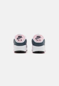 Zapatillas Nike Air con upper de malla gris, detalles en cuero azul marino, talón de goma rosa y marca negra en la parte trasera. Suela plana negra.