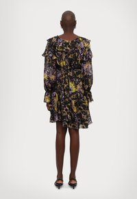 Zwarte jurk met kleurrijke bloemenprint, ruche mouwen en gelaagde rok. Doorzichtige stof met een getailleerde taille. Enkellang met delicate accenten.