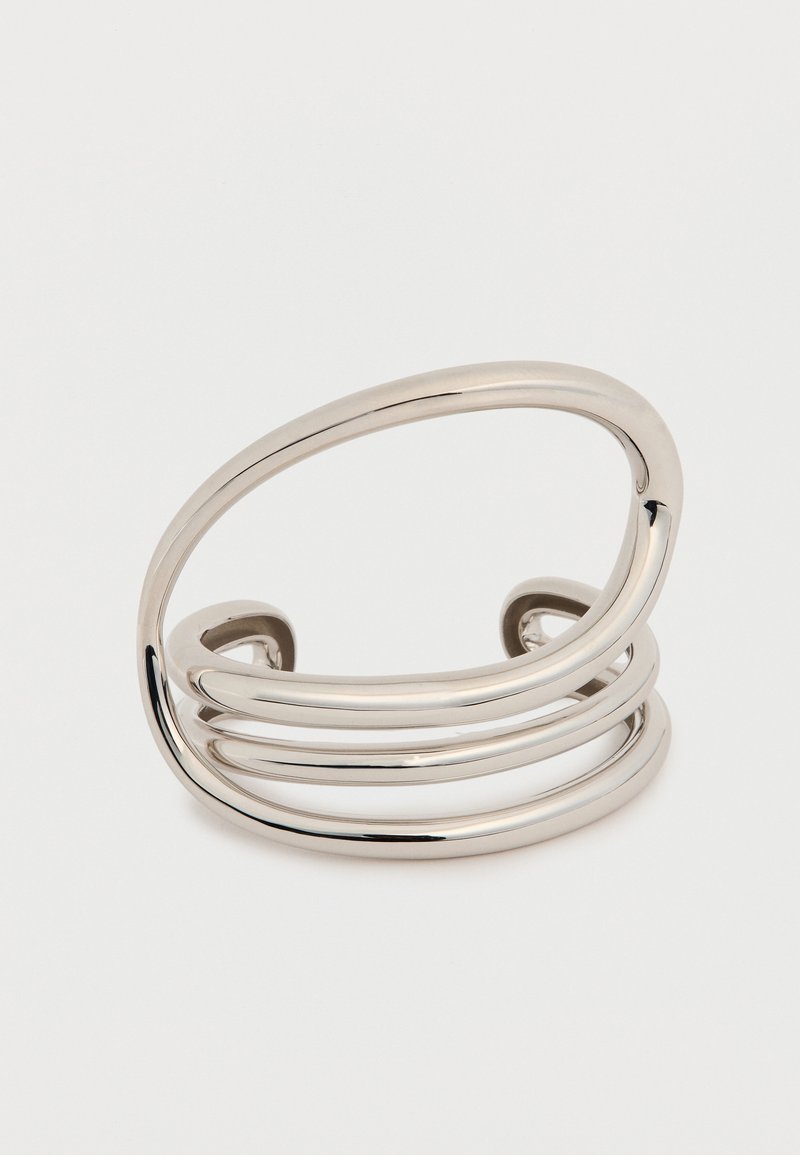 Ασημένιο μεταλλικό βραχιόλι τύπου μανσέτα με τρεις παράλληλες καμπυλωτές λωρίδες, λείο φινίρισμα, ανοιχτά άκρα, μινιμαλιστικό σχέδιο και γυαλιστερή επιφάνεια.