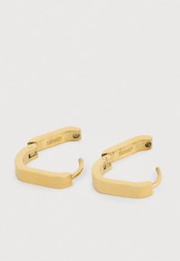 Zlaté kruhové náušnice s geometrickým, ostrým designem. Vyrobené z kovu, mají hladký povrch a bezpečný uzavírací mechanismus.