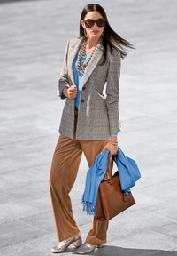 Überprüfter Blazer in Grau und Beige, blaues Oberteil, braune Hose, silberne Schuhe, blauer Schal, braune Handtasche mit Ledertextur.