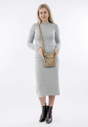 Gold crossbody bag with three zippered compartments, textured surface, and slim design, held by a model in a gray dress and black ankle boots.