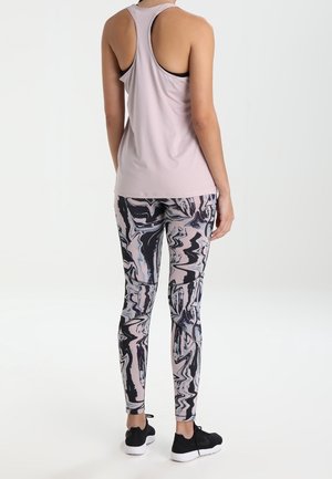 Débardeur rose clair avec un dos nageur, associé à des leggings marbrés noirs, blancs et gris. Des chaussures de sport noires complètent la tenue.