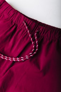 Μπορντό μαγιό με ελαστική μέση, με κορδόνι σε πλεκτό μοτίβο με λευκές λεπτομέρειες. Απαλό, ελαφρύ υλικό.