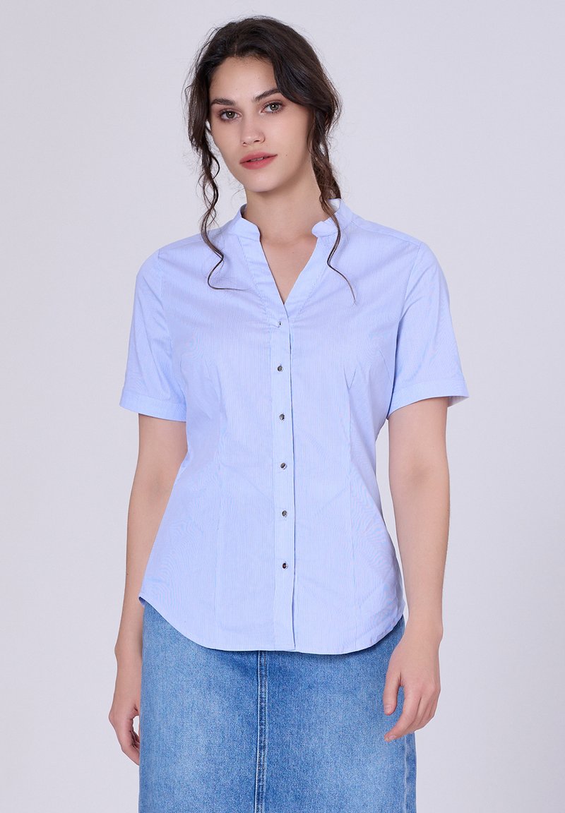 Chemise à manches courtes bleu clair avec décolleté en V, rayures verticales et boutons argentés sur le devant. Tissu lisse et léger.