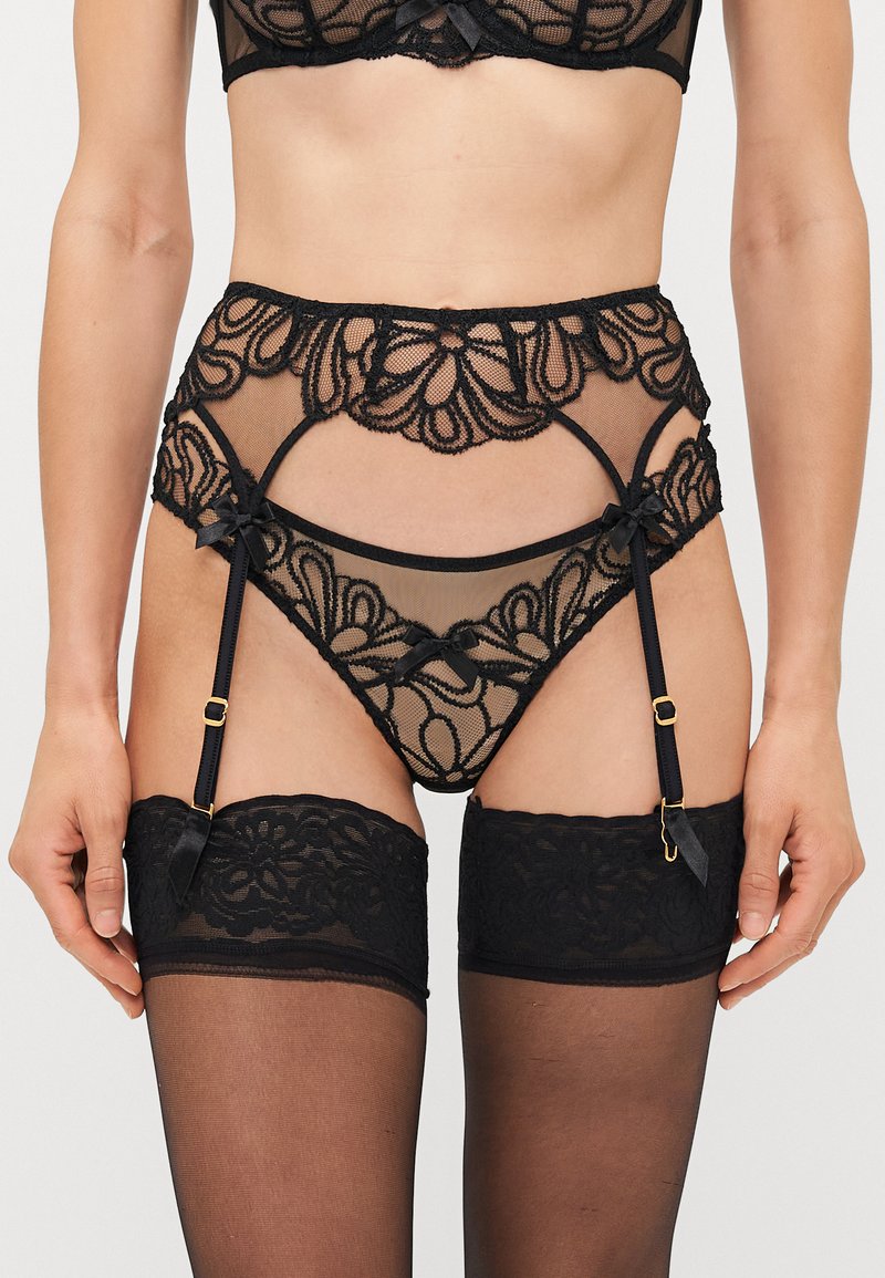 Ensemble de lingerie en dentelle noire avec un design en mesh transparent, des motifs floraux, des nœuds en satin et des porte-jarretelles ajustables avec des accents en métal doré.