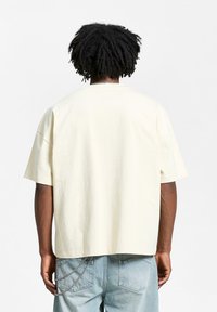 Kremfarget, oversized bomull t-skjorte med rund hals og kortermet, med et enkelt design og uten synlige grafikker.