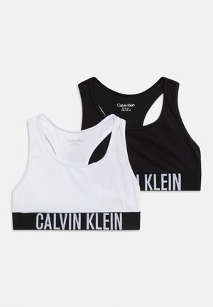 Kaks Calvin Kleini spordiribade komplekti, üks valge ja teine must, mõlemal bränditud elastsed ribad ja racerback-disain, paigutatud valgele taustale.