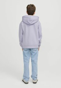 Felpa con cappuccio di colore viola chiaro realizzata in tessuto morbido, abbinata a jeans blu chiaro. La felpa presenta una vestibilità comoda e polsini a coste.