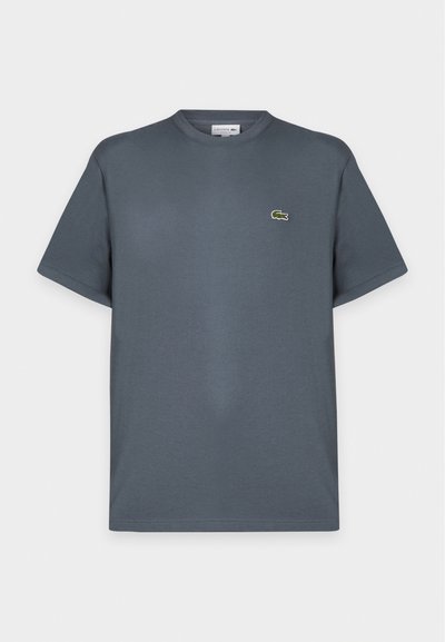 T-shirt gris foncé à manches courtes et col rond avec un petit logo crocodile vert sur la poitrine gauche, présenté sur un fond clair uni.