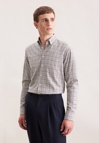Gekleed met een geruit shirt in bruin en wit, met een button-down kraag, lange mouwen en een relaxte pasvorm. Draag het met marineblauwe broek.