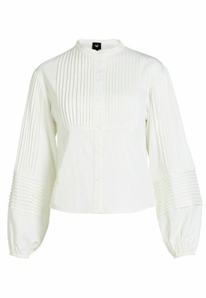 Valge nööpidega pluus, mille esiosas ja varrukatel on vertikaalsed voldid, bandi krae ja veidi puhv varrukad, mis on kogutud.