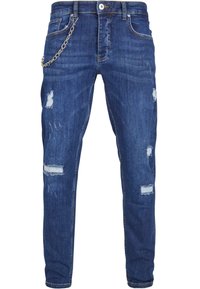 Blå denimjeans med slim fit, som har slitte lapper og en kjedeakzent festet ved hoften. Sømmen er synlig gjennom hele buksen.