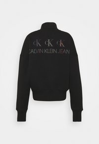Sudadera negra recortada con cuello alto, con logo multicolor "CK" y "CALVIN KLEIN JEAN" bordados en la espalda. Textura suave.