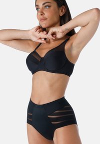 Set di reggiseno nero e slip a vita alta realizzato in tessuto morbido con inserti in rete trasparente e righe verticali, caratterizzato da un design strutturato.