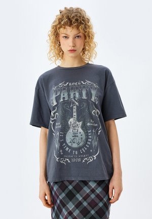 Grå bomulds t-shirt med et vintage guitar grafik med vinger og tekstdetaljer. Kortærmet, rund hals, afslappet pasform.