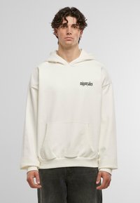 Felpa in cotone color crema con tasca frontale, cappuccio con cordino e testo nero "migonazales" stampato sul petto. Design con vestibilità rilassata.