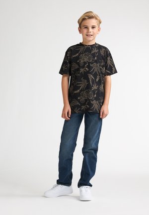 Tricou negru cu mâneci scurte și model floral aurit, asortat cu blugi albaștri și teniși albi. Tricoul are croială lejeră și decolteu rotund.