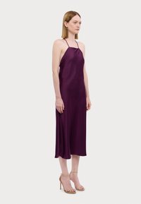 Abito midi in satin viola con design a collo all'americana, texture liscia e silhouette fluida. Indossato con sandali beige con cinturini e tacco alto.