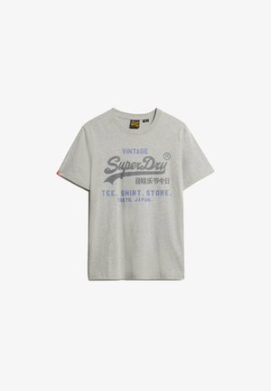 Camiseta de algodón gris con mangas cortas, cuello redondo y gráficos impresos en azul y negro que incluyen "SuperDry" y "Tokio, Japón."