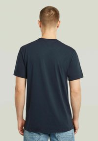 T-shirt in cotone blu navy con maniche corte e collo tondo, caratterizzato da una texture liscia e una vestibilità rilassata. Nessun motivo o grafica visibile.