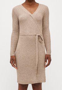 Robe cache-cœur en maille marron clair, avec un motif côtelé vertical, manches longues, décolleté en V, et ceinture nouée à la taille pour une silhouette ajustée.