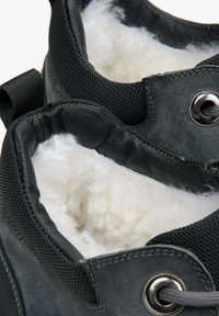 Czarne botki mają miękką, białą futrzaną podszewkę, teksturowaną czarną skórzaną powierzchnię oraz metalowe oczka na sznurówki. Gładki i wyraźny design.