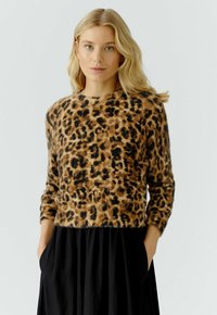 Leopardprint sweater van zachte, fuzzy stof, met lange mouwen en een ronde halslijn. Draagt met een zwarte, vloeiende rok.