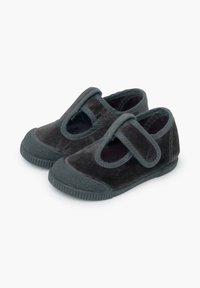 Scarpe in velluto grigio scuro con punta arrotondata, fascia in velcro e suola in gomma. Presentano dettagli laterali a taglio e accenti testurizzati.