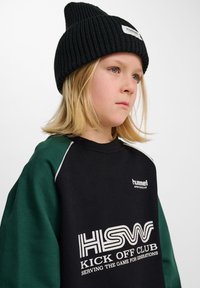 Svart sweatshirt med gröna ärmar, med vitt logotyp- och textdesign. Ribbad svart mössa ger textur och fulländar den sportiga outfiten.