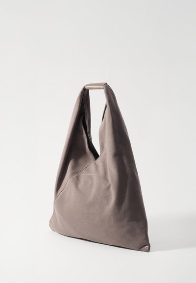 Grand sac en tissu taupe avec une forme triangulaire unique. Il présente une texture douce et une simple poignée en boucle sur le dessus.