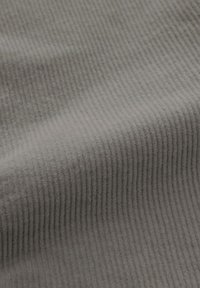 Tessuto grigio a coste che mostra motivi di texture verticali. Il materiale appare morbido, con un aspetto accogliente e invitante grazie alla sua consistenza pelosa.