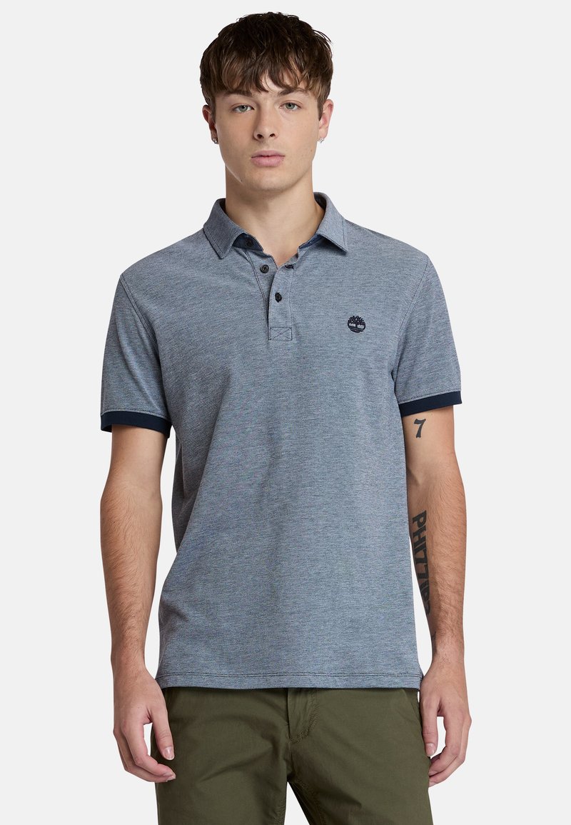 Miestenská polo košeľa v melírovanej šedej farbe, zmes bavlny, s klasickým golierom, trojzakladovým zapínaním a námorníckymi manžetami. Logo Timberland na hrudi.