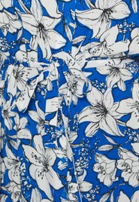Květinové šaty s jasně modrým podkladem a velkými bílými a černými lilie. Mají knoflíky a zavazování v pase pro větší detail.