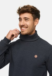 Granatowy sweter golfowy o prążkowanej teksturze, z małym okrągłym logo na piersi. Wygodne dopasowanie z wydłużonym kołnierzem.