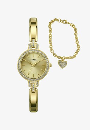Guld Timex-ur med krystalaccenter og et matchende guldkædearmbånd med en hjerteformet vedhæng med krystaller.
