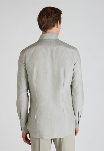 Camisa abotonada de color gris claro con un corte ajustado, textura suave y dobladillo curvado. Mangas largas con puños abotonados y un diseño liso y sencillo.