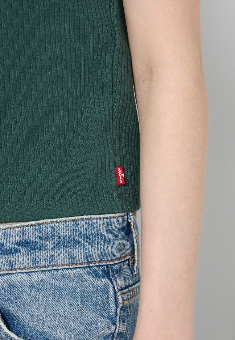 Geripptes grünes Spitzenoberteil mit einem roten Levi's-Label, kombiniert mit hellblauen Denim-Shorts mit einer verblassten Waschung und sichtbaren Nähten.