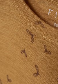 Senapsgul T-shirt med en texturerad stickning, prydd med mörkbruna abstrakta mönster och en ribbad halsringning.