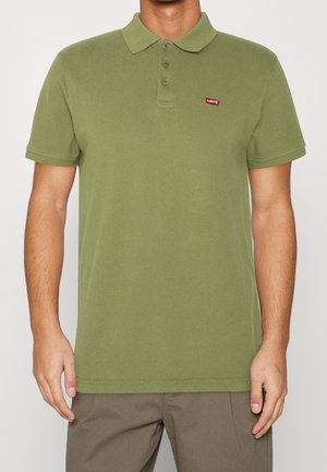 Oliwkowa koszulka polo wykonana z bawełny, z klasycznym kołnierzykiem, trzema guzikami oraz małym czerwoną logo Levi's po lewej stronie klatki piersiowej.