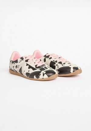 Die Sneaker haben ein schwarz-weißes Kuhmuster, mit pinken Schnürsenkeln und Innenfutter. Die Sohle besteht aus braunem Gummi. Hergestellt aus glattem synthetischem Material.
