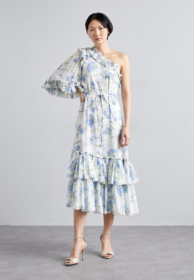 Bloemige midi-jurk met blauwe bloemen op een witte achtergrond, één schouder met ruches en een gelaagde ruffle onderrand. Zachte stof, ontspannen pasvorm.