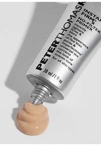 Tubo argentato del primer Peter Thomas Roth Instant Firmx No-Filter con un vortice di crema beige chiaro che fuoriesce dal beccuccio.