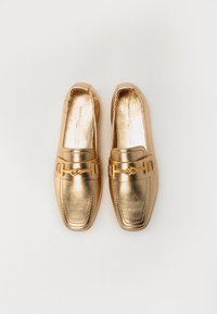 Mocassins en cuir doré avec un bout carré, ornés d'une chaîne décorative en or sur le devant et d'une texture lisse et brillante.