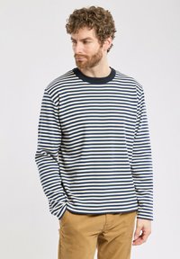 Gestreiftes Langarmhemd mit horizontalen Streifen in Marineblau und Cremé, gerippter Marineblau Rundhalsausschnitt, lockere Passform, aus Baumwollmaterial.