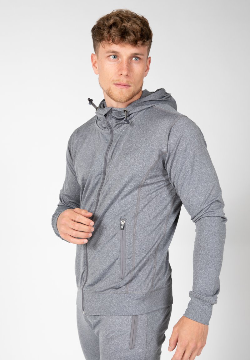 Grijze sportjack met ritszakken, een capuchon en structuurstof, met een slim fit en subtiele stikseldetails.