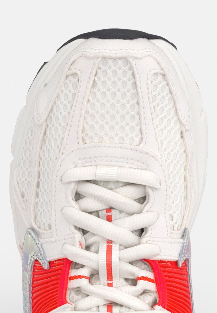 Chaussure de sport en mesh blanche avec des accents rouges et des panneaux texturés, présentant un design épuré, un bout rond et des lacets plats. Semelle extérieure noire.