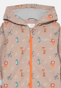Kinderregenjacke in hellbeige mit Tiermotiven. Verfügt über einen orangen Reißverschluss und eine Kapuze, aus wasserdichtem Material. Größe 128.